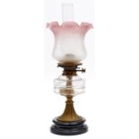 An Edwardian brass oil lamp, c1910, with moulded glass fount, on black glazed earthenware base and