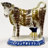 A Prattware cow creamer, early 19th c, sponged in manganese and sepia, the diminutive milkmaid in