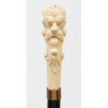 An ebonised walking cane, late 19th c, the bone handle carved with a grotesque horned head,