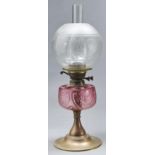 An Edwardian brass oil lamp, with moulded cranberry glass fount and brass burner, etched glass