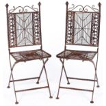A pair of cast metal garden chairs, the ornate s-scroll top rails above spider's web splats