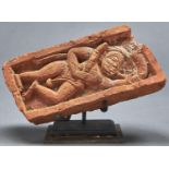 An Indian fired clay brick with deity in relief, 19th c, 24cm l, metal stand Some damage as
