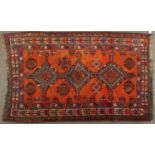 A Kazak style rug, the orange field worked with three geometric medallions, barber medallions and