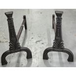 A pair of cast iron andirons in 16th c style, headed by stylised masks above tapered foliate and