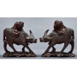 A pair of Chinese hardwood figures of mounted water buffalos , on shaped carved bases, black glass