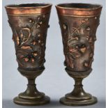 A pair of pewter cased goblets, the bodies coppered cast dragonfly, strawberries and hazelnut