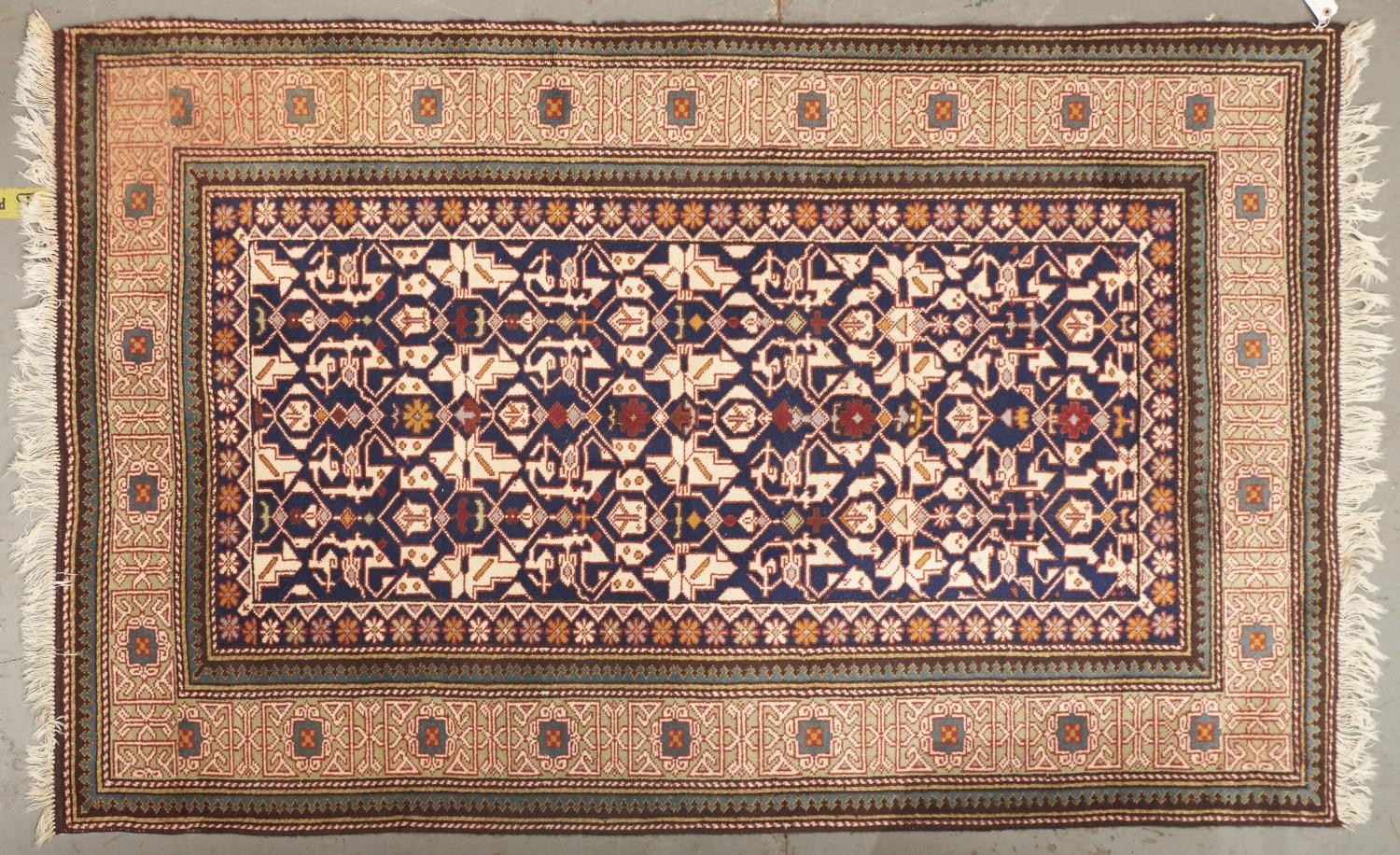 A modern Caucasian coloured bordered rug, the indigo field worked with stylised flowerheads and leaf