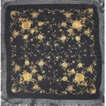 A black cotton table cloth, worked in silk with flowerheads and leafage in apricot - ivory, fringed,