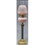 A Victorian brass mounted columnar oil lamp, c1900, with serpentine shaft and pink satin glass