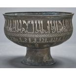 A Seljuk Khorasan inlaid bronze pedestal bowl, of ogee form with bands of mask headed and Kufic