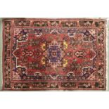 A modern Caucasian multicoloured bordered rug, the pale red ground worked with a central medallion