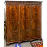 A mahogany triple wardrobe in George III style, flared cornice above a frieze applied shell and