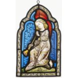 A Victorian painted stained glass small arched panel of a trumpeting angel with blue scrolling