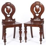 A pair of Victorian oak hall chairs, c1870, the backs panelled at the top with circular centres