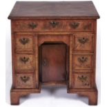 A George II walnut kneehole desk or dressing table, the quarter veneered top with moulded lip and