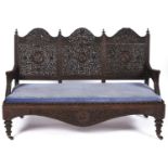 An Indian carved hardwood triple arch back sofa, late 19th c, finely pierced and carved with flowers