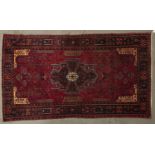 A modern Caucasian bordered rug, the claret field worked to the centre with a black, pink, turquoise