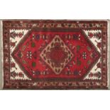A Bokhara rug, the red field worked with three rows of fifteen oval medallions flanking hooked