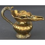 An Islamic brass oil lamp of squat fluted baluster form, the shaped top with scaled spout and