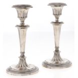 A pair of George V silver candlesticks, in neo classical style, of fluted form on oval foot,