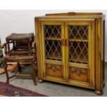 An art deco style oak display cabinet with shallow upstand, enclosed by a pair of lead glazed