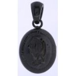 A Victorian jet mourning locket, c1870, carved with a monogram within Greek key border, 70mm overall