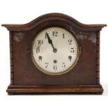 A mahogany mantel clock, c1930, the cavetto moulded serpentine cornice above a veneered front with