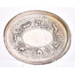 An Indian oval silver repoussé tray or stand, early 20th c, worked with a continuous jungle scene