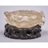 A Chinese rock crystal brush washer, carved with prunus, 15cm l, wood stand (2) Good condition