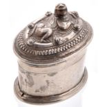 A Burmese oval silver lime box and repousse cover, early 20th c, the cover worked with a recumbent