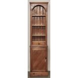 A narrow pine bookcase, flared cornice, arched open top with drawer, the projecting base enclosed by