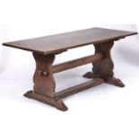 A reproduction oak refectory table, in 17th c style, the top above shaped trestle ends joined by