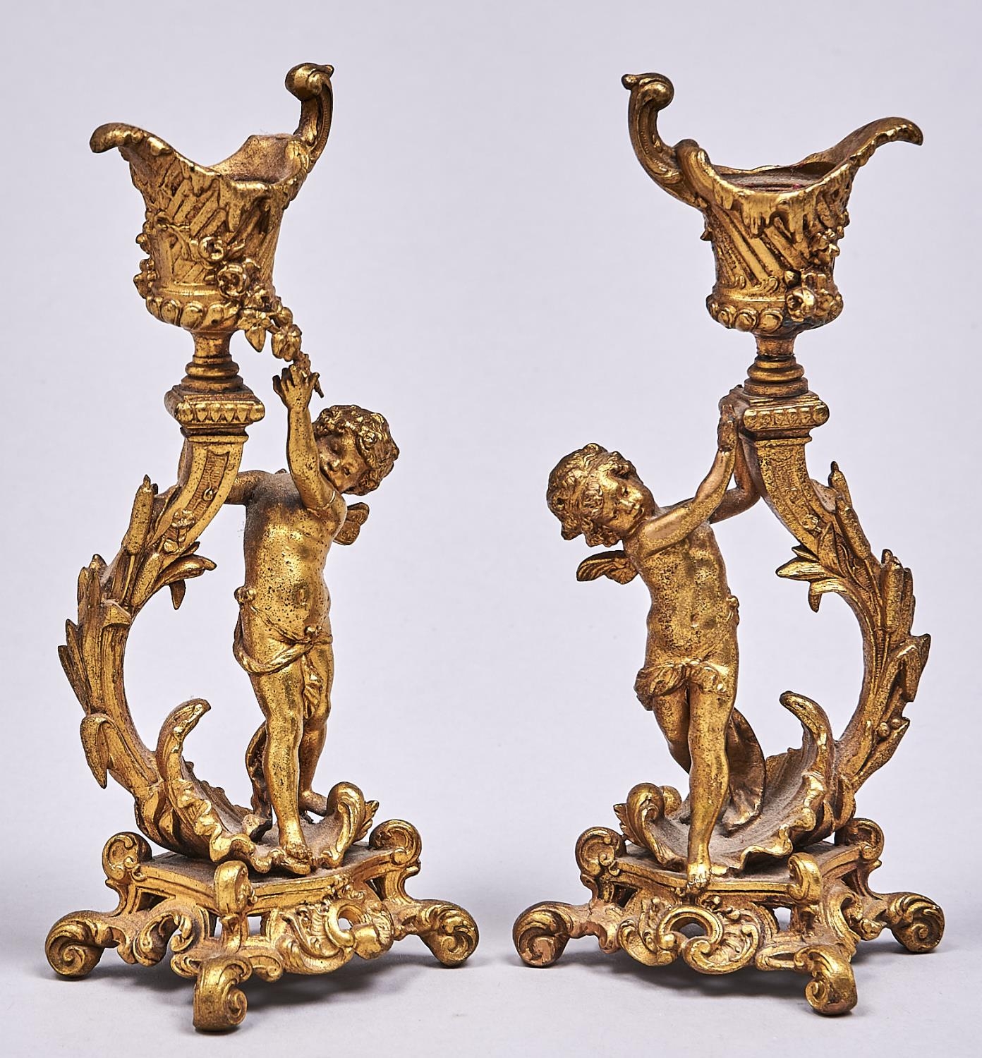 A pair of French fin de siecle spelter gilt Putto figural candlesticks in rococo style, c1910, in