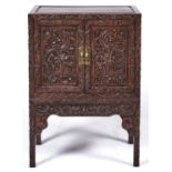 A Chinese hardwood cabinet, early 20th c, panelled doors, front and sides, carved with dragons, bats