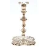 A George II silver taperstick, with square nozzle, banded sconce and knopped stem, on shell cornered