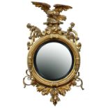 A George IV circular giltwood and composition eagle mirror, c1830, the convex plate in reeded