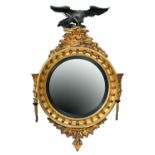 A George IV circular giltwood mirror, c1830, the convex plate in reeded ebonised slip and cavetto