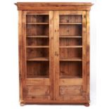 A waxed pine cabinet, early 20th c, with adjustable shelves and enclosed by partly panelled glazed