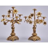 A pair of French fin de siecle gilt brass candelabra, in the form of lilies held aloft by a child,