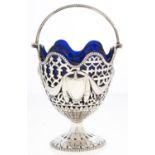 A George V neo classical style pierced silver sugar basket, with beaded swing handle, blue glass