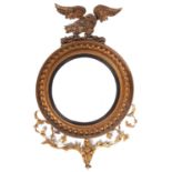 A George IV giltwood and composition eagle mirror, the convex plate in reeded circular ebonised slip