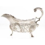 A George III silver sauce boat, spirally fluted and chased with flowers, leaf capped flying scroll