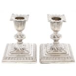 A pair of Victorian dwarf silver candlesticks, wrythen fluted, on stepped square foot, nozzles, 90mm