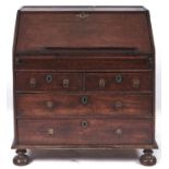 A George II oak bureau, with stepped interior of drawers and pigeon holes with well and sliding