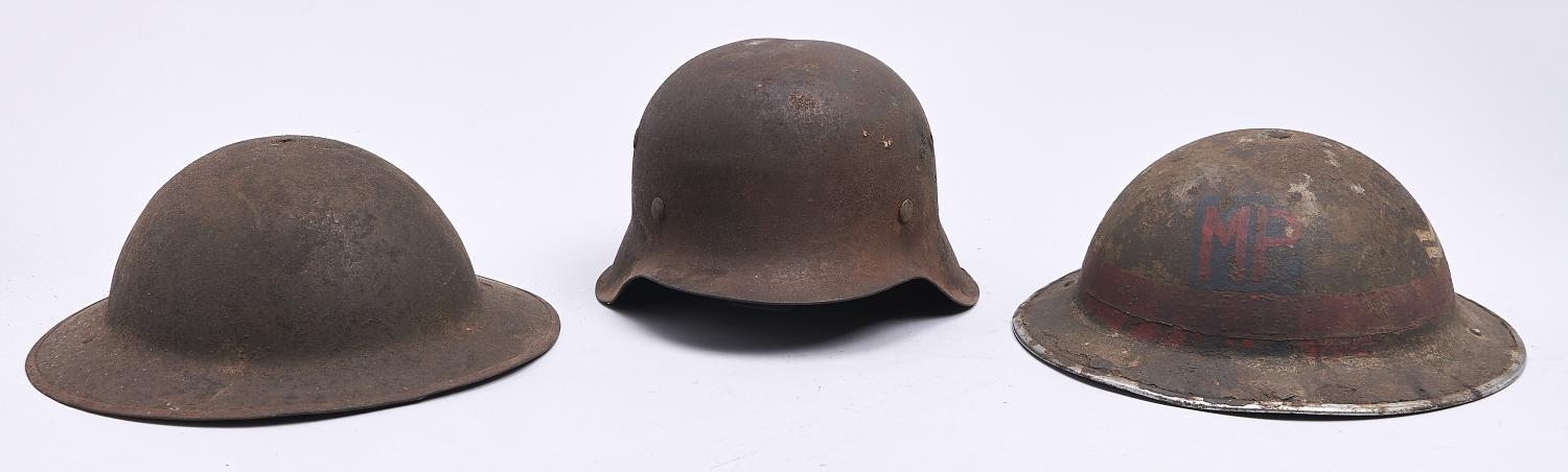 A German, Third Reich soldier's steel helmet and two contemporary British military steel helmets,