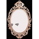 An oval giltwood mirror, 19th c, the bevelled plate in ribbon-and-leaf frame, crested by c-scrolls