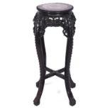 A Chinese carved hardwood stand, c1900, with pink stone inset circular top and profusely carved