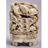 A Japanese ivory okimono, Meiji period, carved with turtles clambering on rocks, on integral base