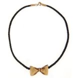 A 9ct gold bow pendant, on black silk cord with 9ct gold ends, 5.7g Good condition