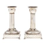 A pair of Edwardian silver dwarf columnar candlesticks, on pierced square base and bun feet,